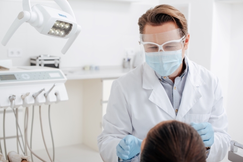 Dentist looks at patient's mouth