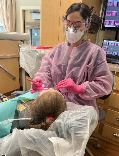 Dental hygienist cleans child's mouth
