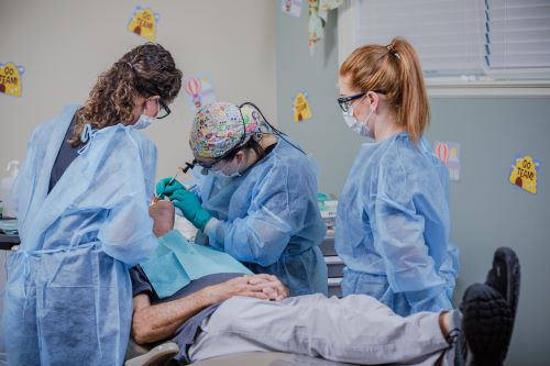 three dental team members examine patient's mouth