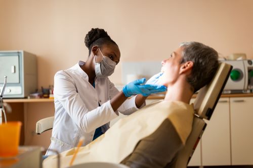 dental team member wearing gloves and mask looks in patient's mouth