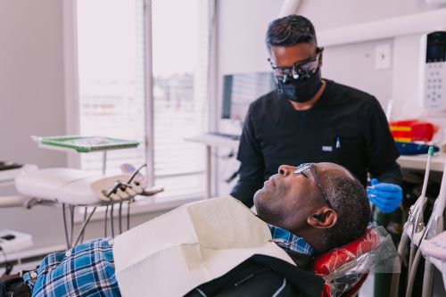 dental team member wearing gloves, mask, and protective eyewear examines patient