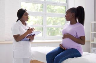 pregnant woman holding belly at doctor's office