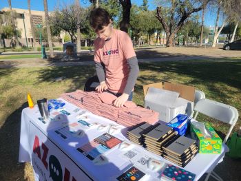 Man wearing AZOHC shirt organizes shirts outside capitol
