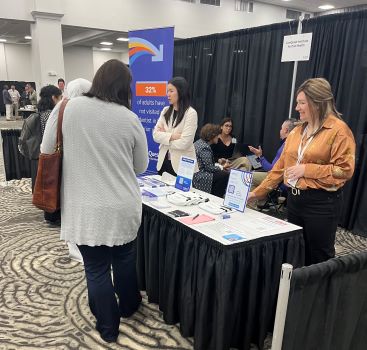 Rebecca Preston and Hannah Cheung talking to people at CareQuest Institute booth