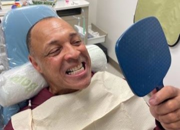 Veteran smiling in the mirror after teeth cleaning