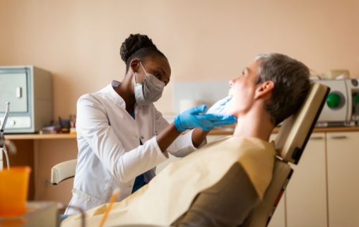 dental team member wearing gloves and mask looks in patient's mouth