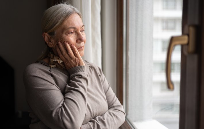 Elderly woman with tooth pain looking out window