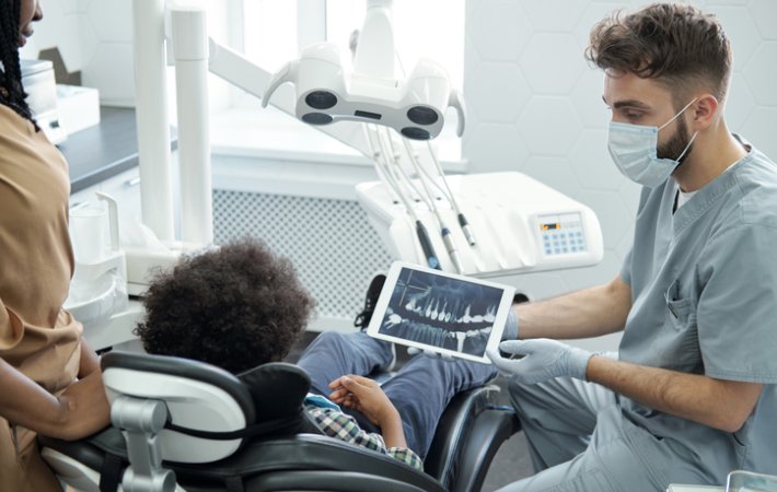Dental hygienist shows child x-ray of teeth