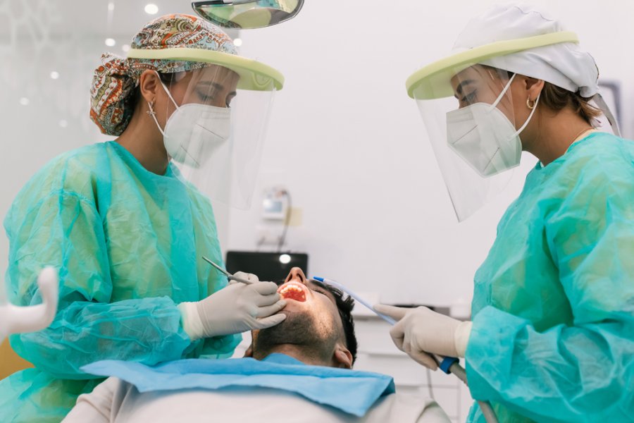 Female dental providers examining a male patient